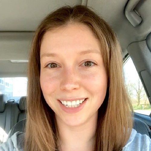 Happy woman smiling in a car interior on a sunny day.
