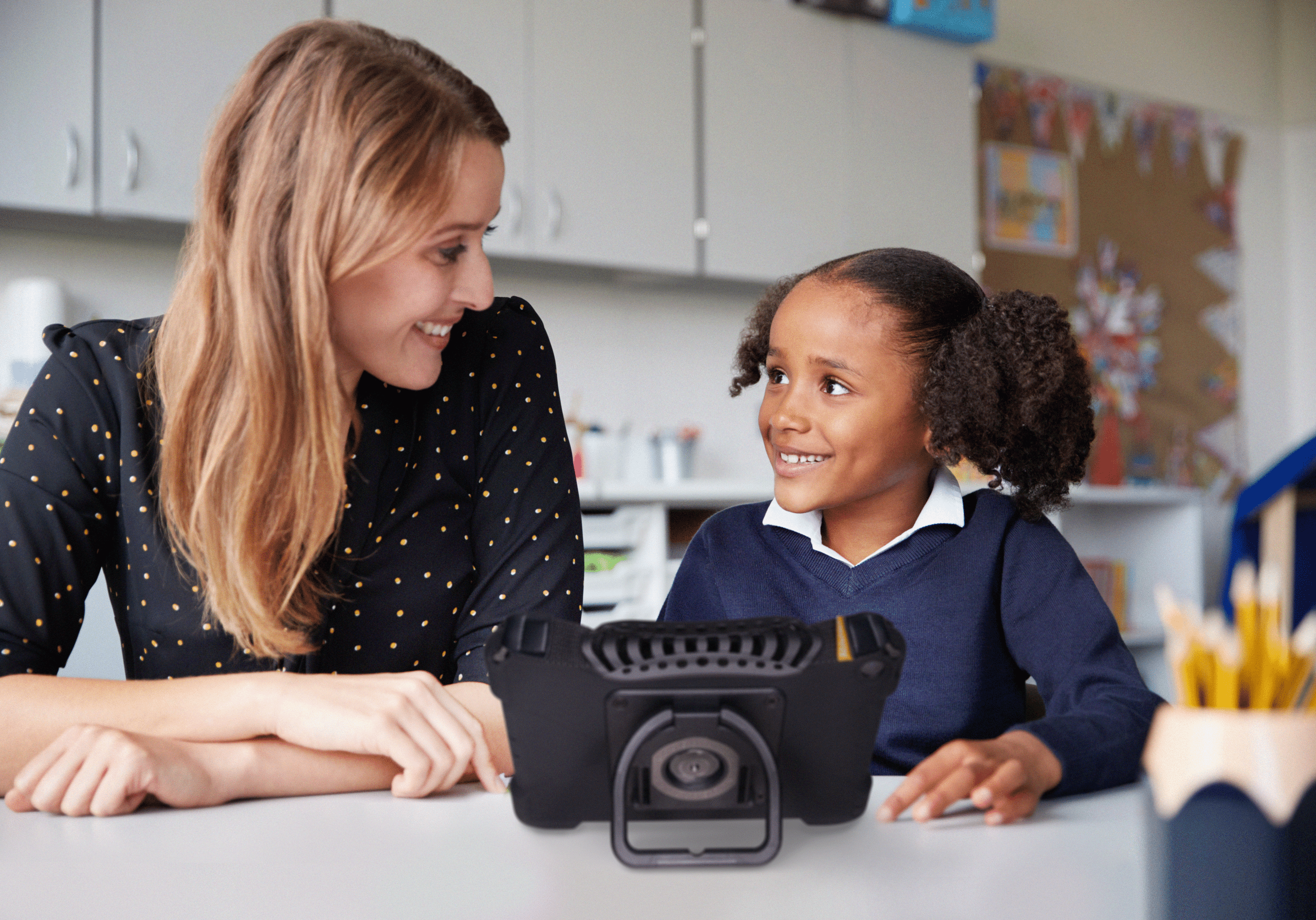 SLP and child engaging with high-tech AAC device for enhanced communication.