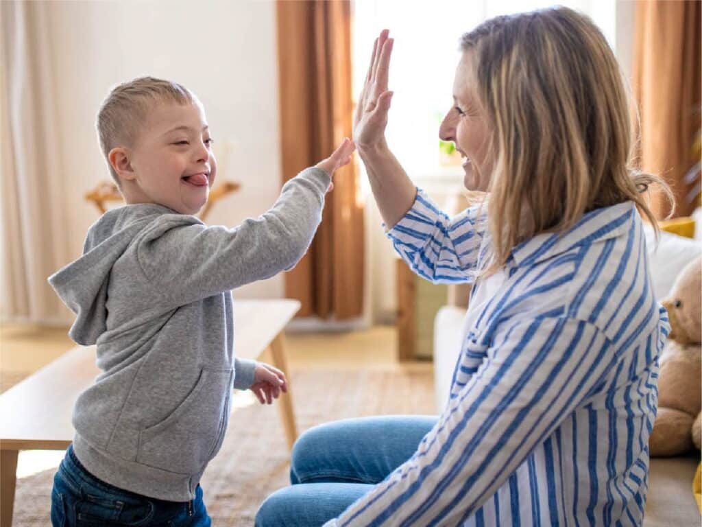 Mother and child share a joyful high-five in a bright, cozy living room.