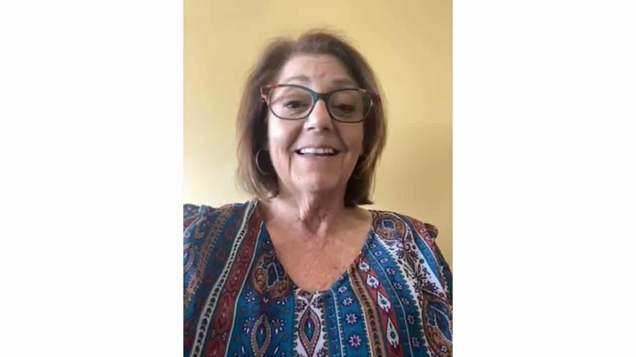 Happy woman smiling brightly with glasses, capturing joyful moments in a vibrant setting.