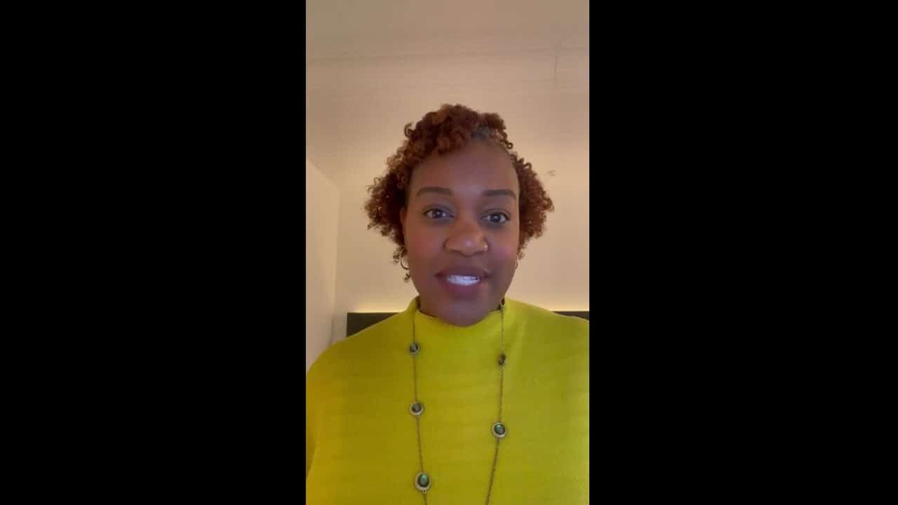 Inspiring speaker sharing bright ideas in a vibrant yellow sweater.