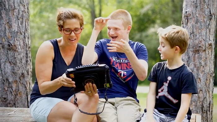 Family laughing together while watching videos outdoors.