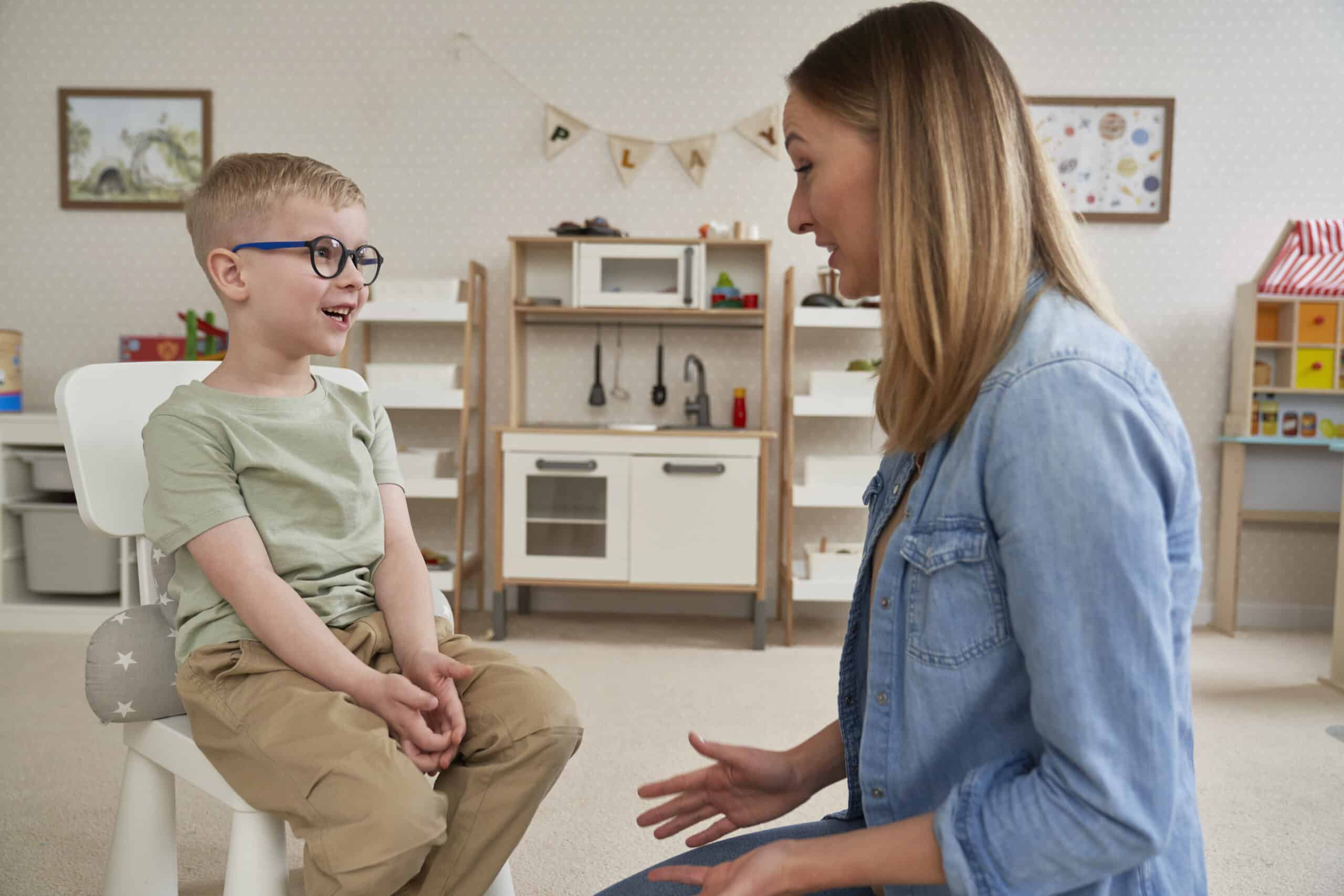 Young boy engages in a therapeutic conversation with a therapist in a playful classroom.
