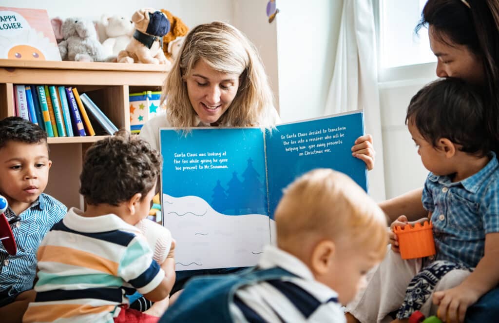 Teacher shares a Christmas story with engaged children in a cozy classroom setting.
