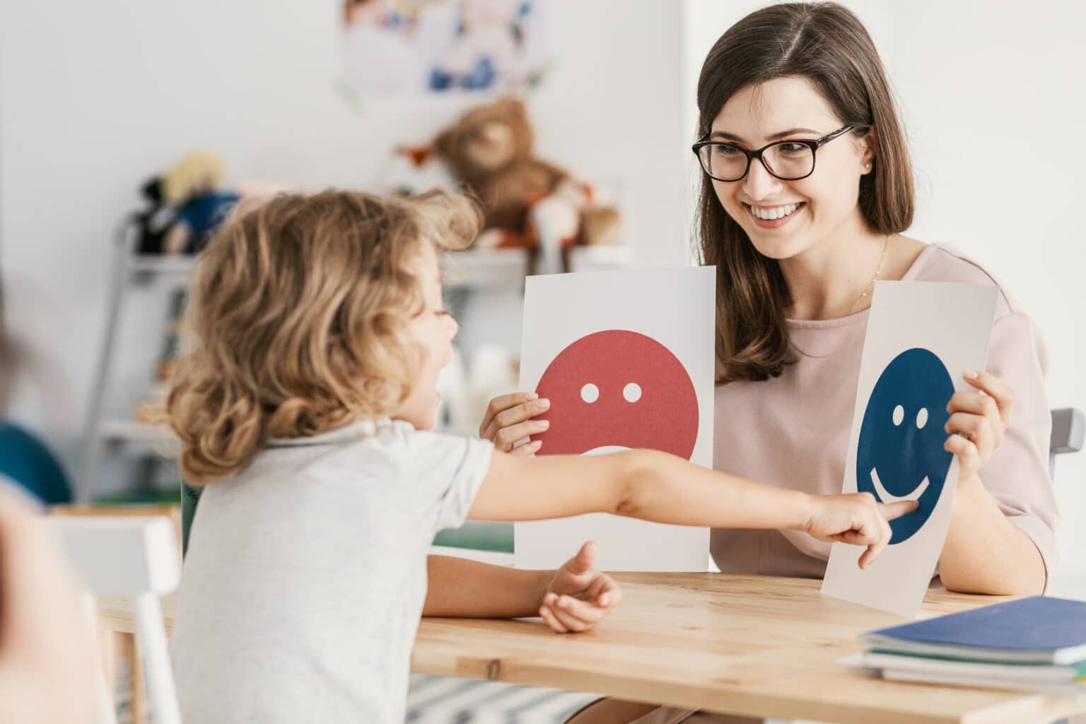 Speech therapist uses emotion emoticons in therapy session with child on autism spectrum.