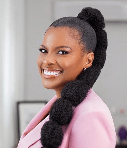 Smiling woman in a pink blazer showcases confidence and style.