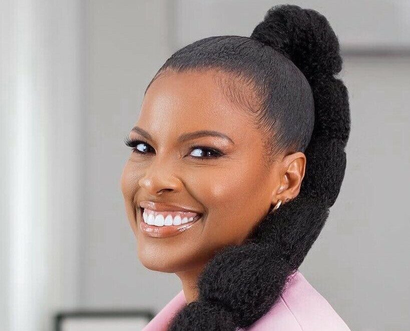 Beautiful woman smiling in a stylish pink blazer with unique hairstyle.
