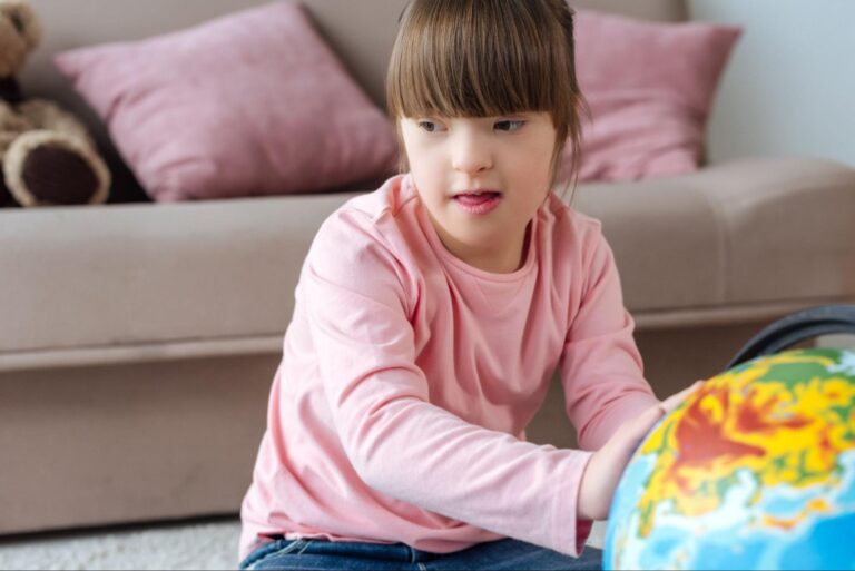 Child exploring a colorful globe indoors, learning about the world around her.