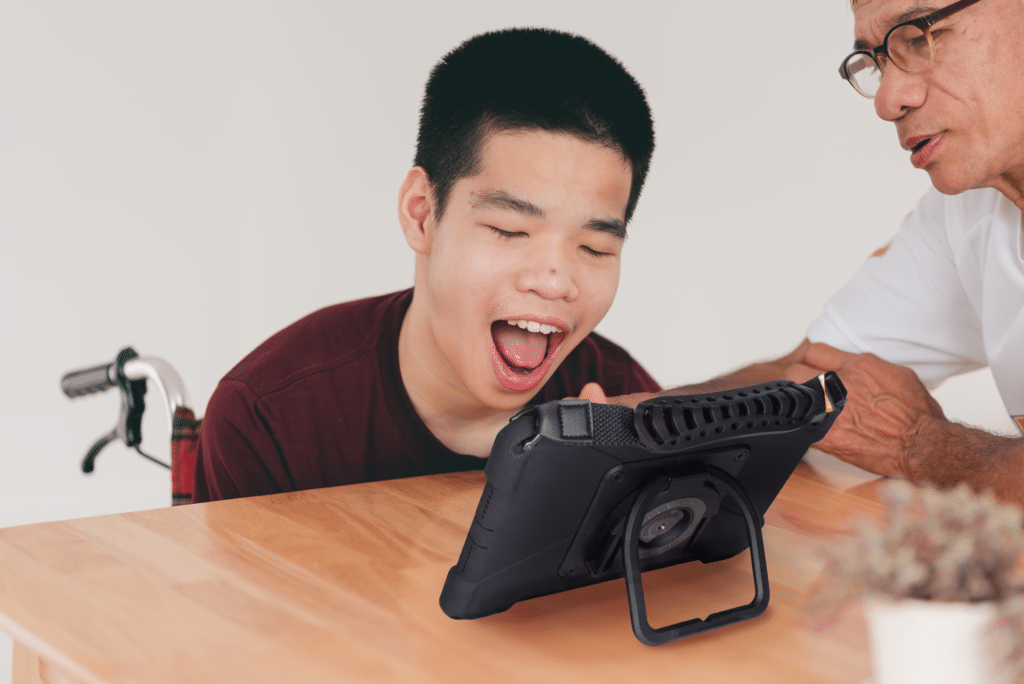 A joyful child engages with a tablet while learning with a mentor.