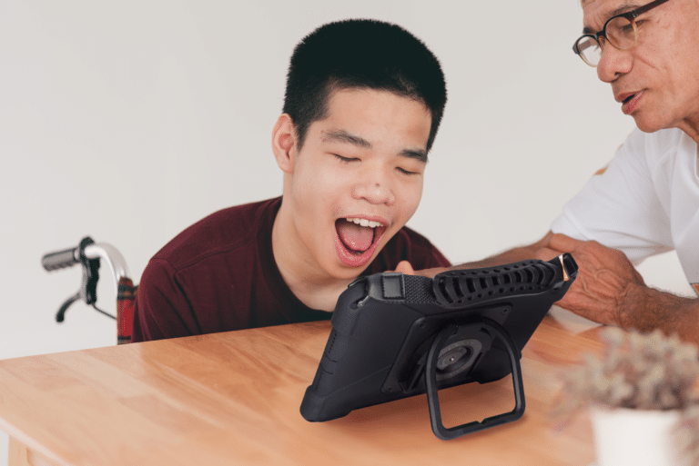 A joyful child engages with a tablet while learning with a mentor.