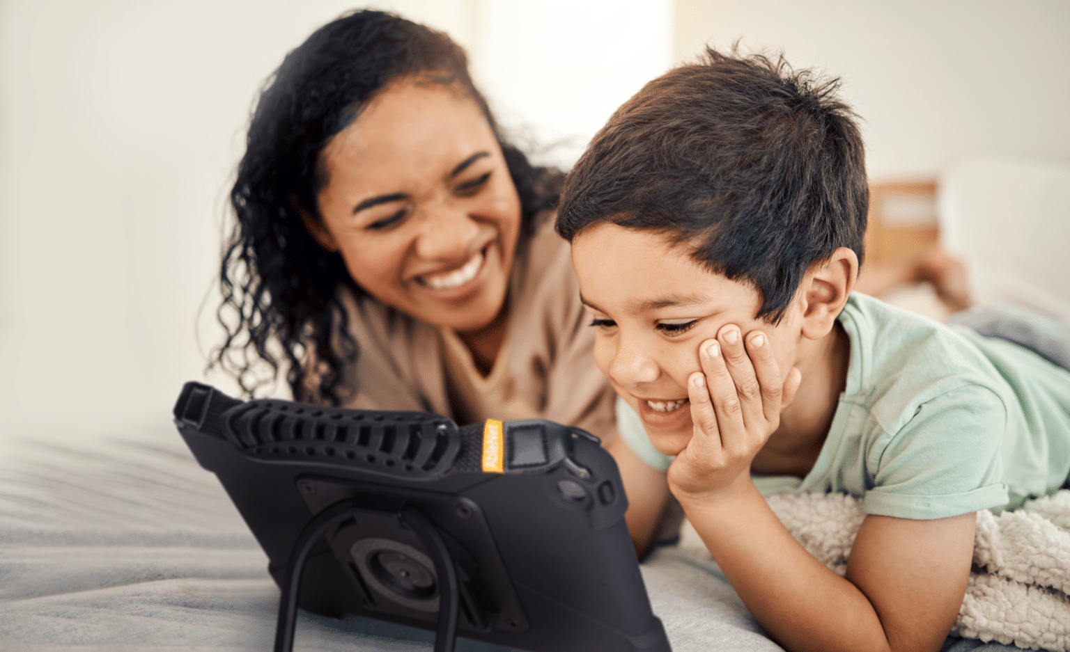 Mom and child enjoying quality time together, watching something on a tablet.