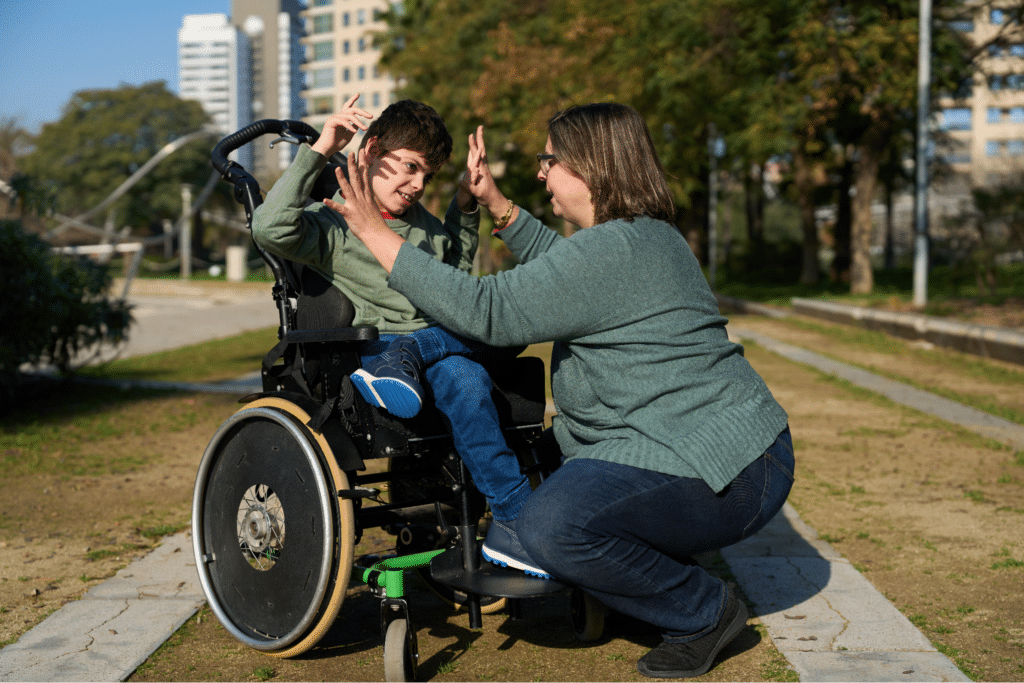 Joyful moments between a caregiver and child in a wheelchair outdoors.
