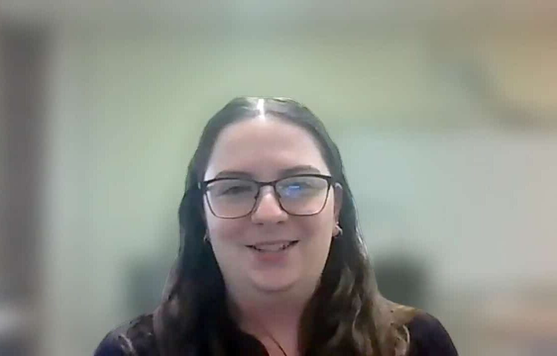 Smiling person with glasses, showcasing joy and positivity in a professional setting.