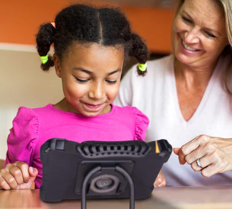 Girl enjoying educational apps on a tablet with an adults support.