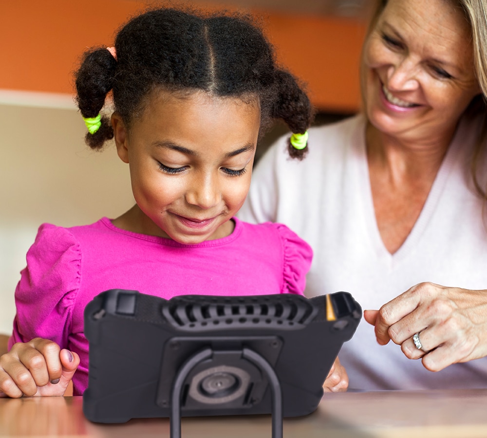 Girl enjoying educational apps on a tablet with an adults support.