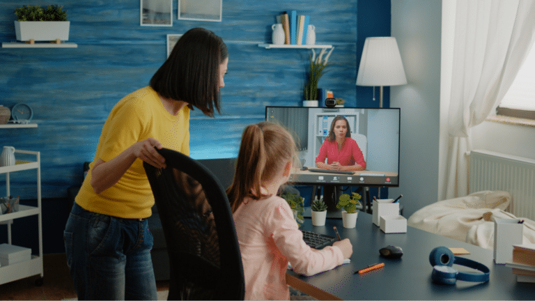 Mother and daughter connect through a virtual meeting on a computer.