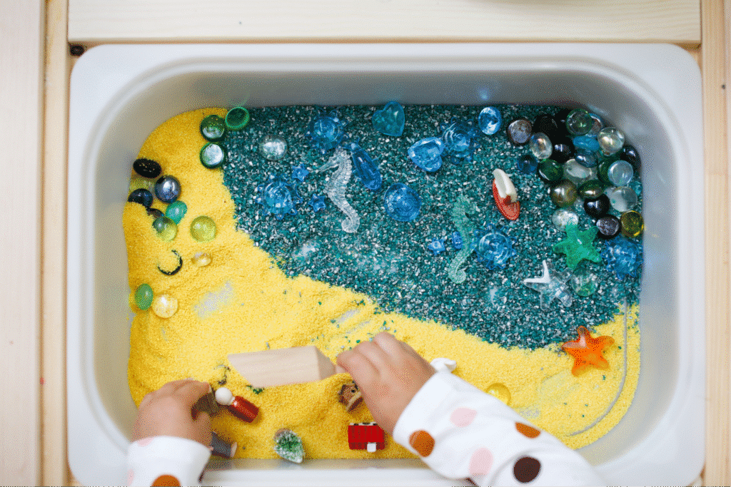 Child plying with sensory beach-themed bin in speech therapy.