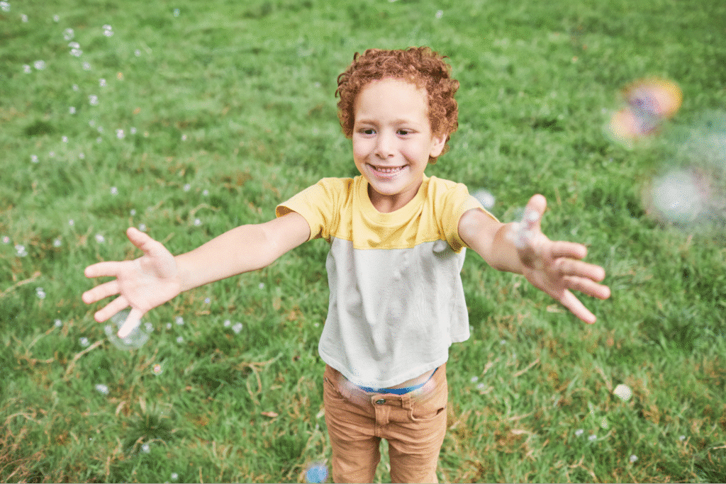 Happy child enjoying bubbles in a green backyard.
