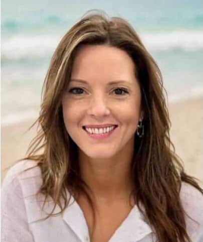 Smiling woman enjoying a sunny day at the beach with beautiful ocean background.