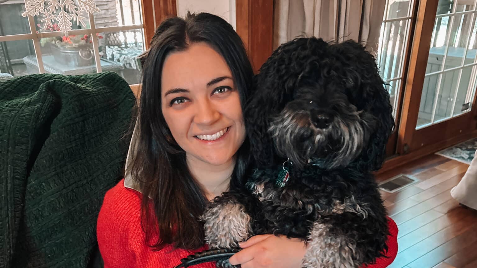 A cheerful woman holding her beloved dog, enjoying a cozy indoor moment together.