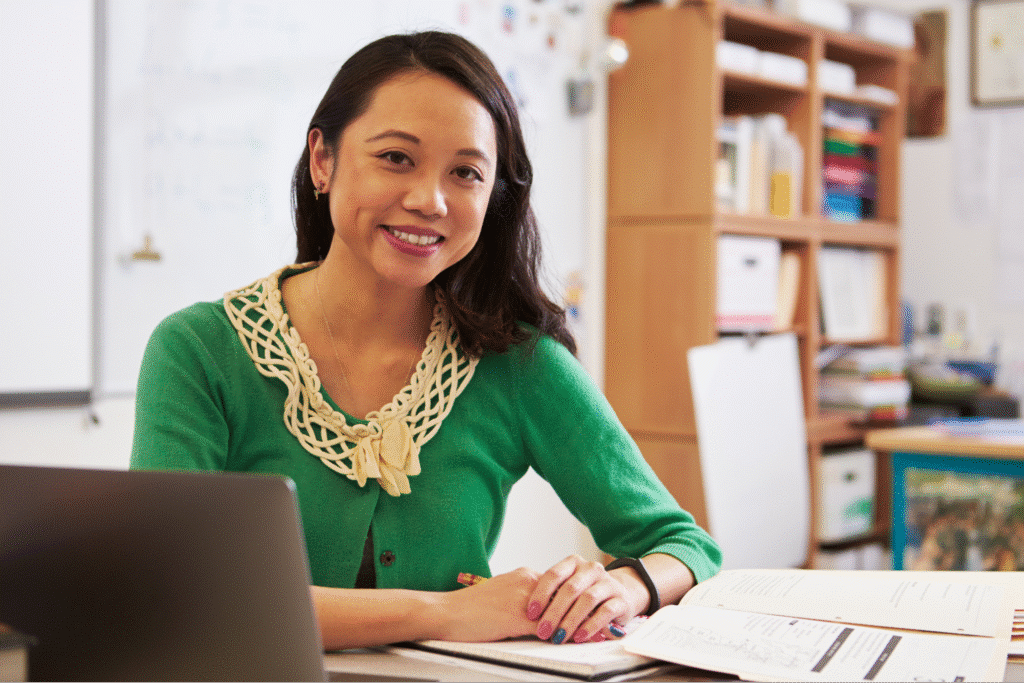 Inspiring teacher smiling in a colorful classroom, promoting a positive learning environment.