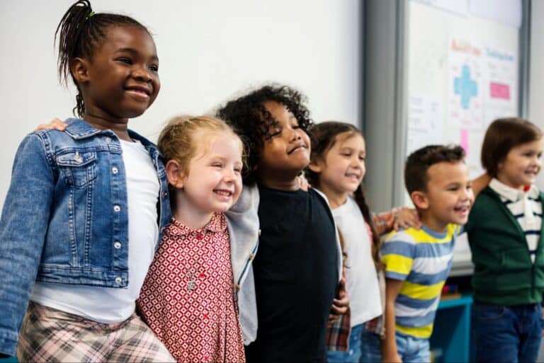 Happy children celebrating friendship and togetherness in a joyful classroom setting.