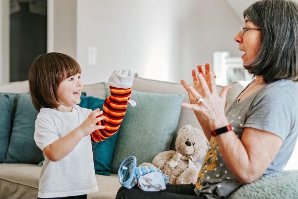 Child and adult engage in playful interaction with a colorful puppet in a cozy living room.