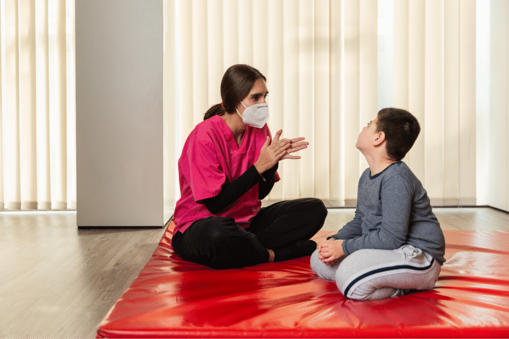 Therapist engaging with a child in a supportive learning environment on a mat.
