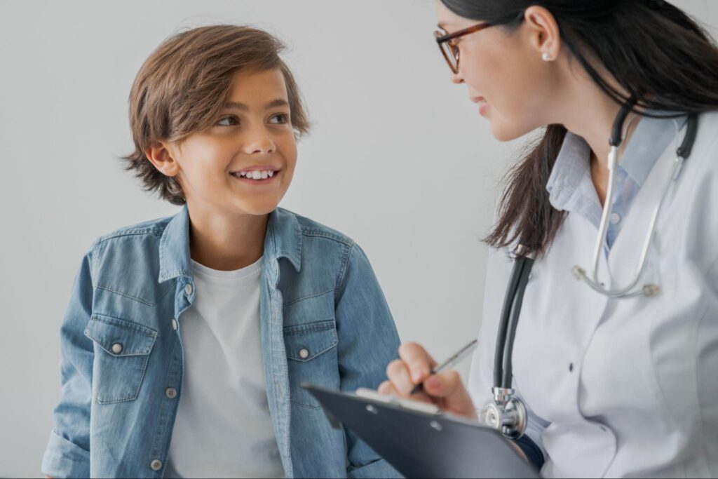 Boy smiling during friendly consultation with a compassionate doctor in a medical setting.