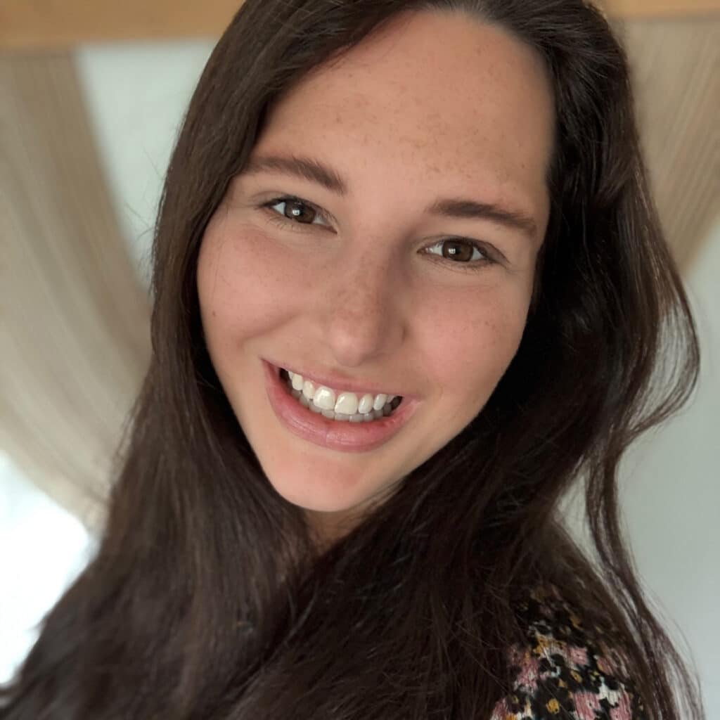 Smiling woman with long hair in a cozy indoor setting, radiating positivity.