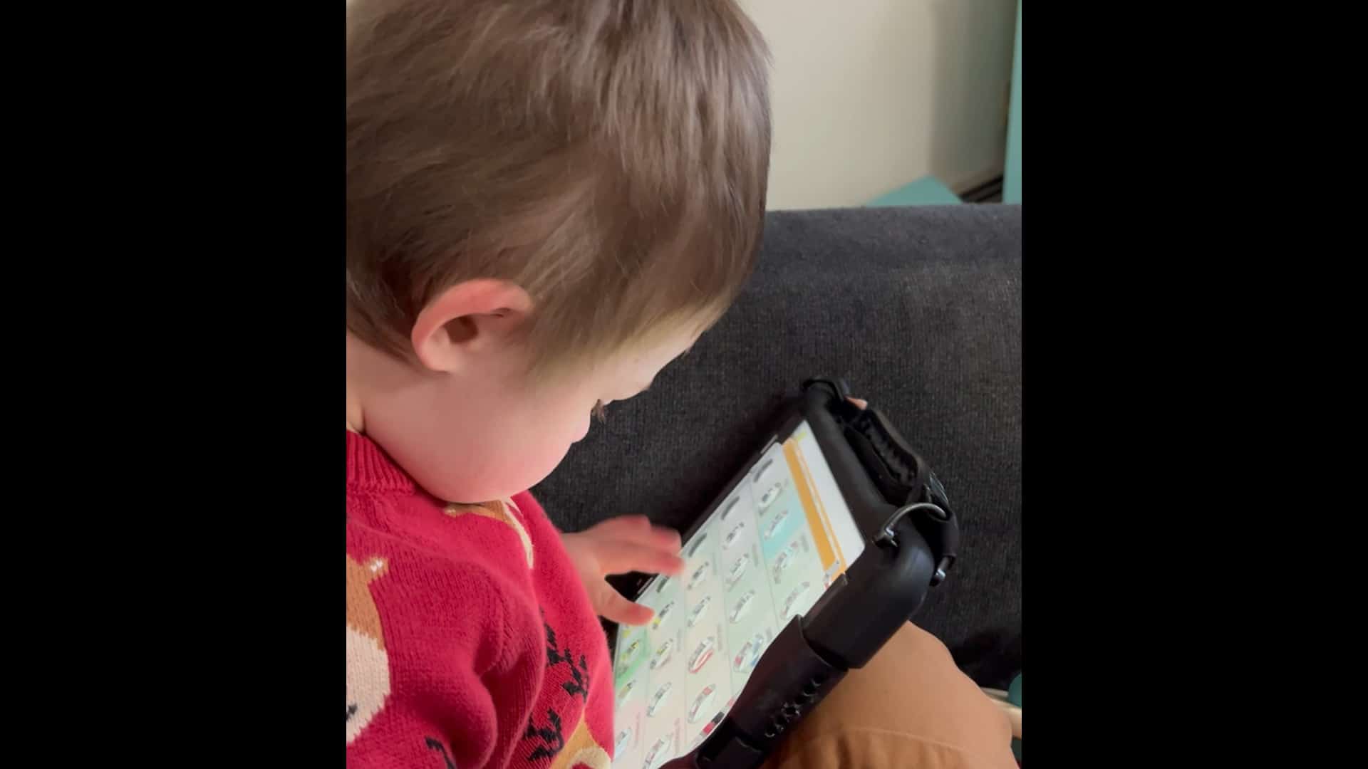 Toddler engaged with educational tablet on a cozy couch.