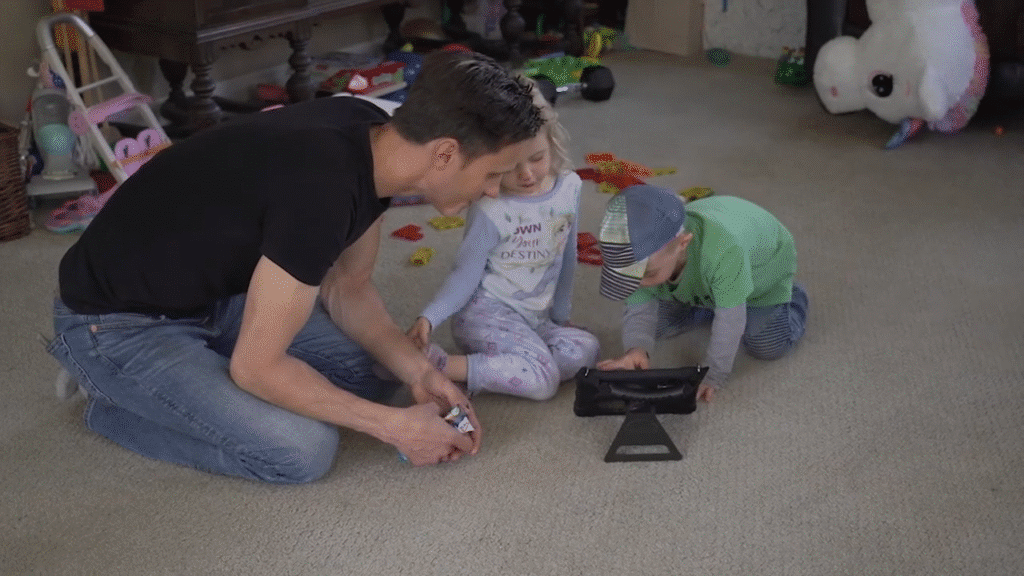 Family playing together with toys and a tablet in a cozy living room setting.