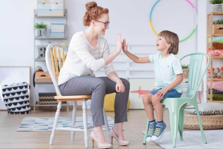 Mom and son playing a fun hand game in a bright, colorful room.