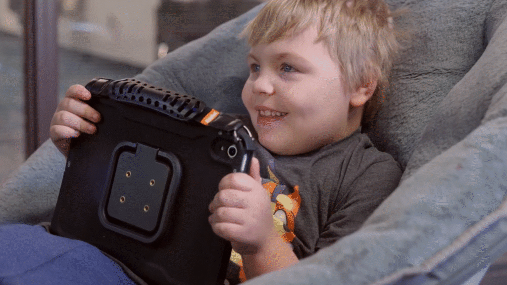 Happy child enjoying a tablet while relaxing in a cozy chair.