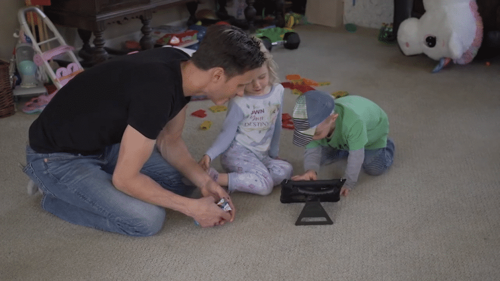 Father playing with kids, engaging in fun activities on a colorful playroom floor.