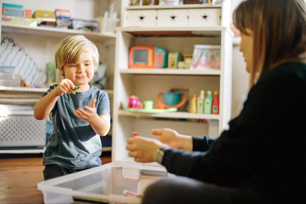 Child playing creatively with toys alongside an adult in a colorful learning environment.