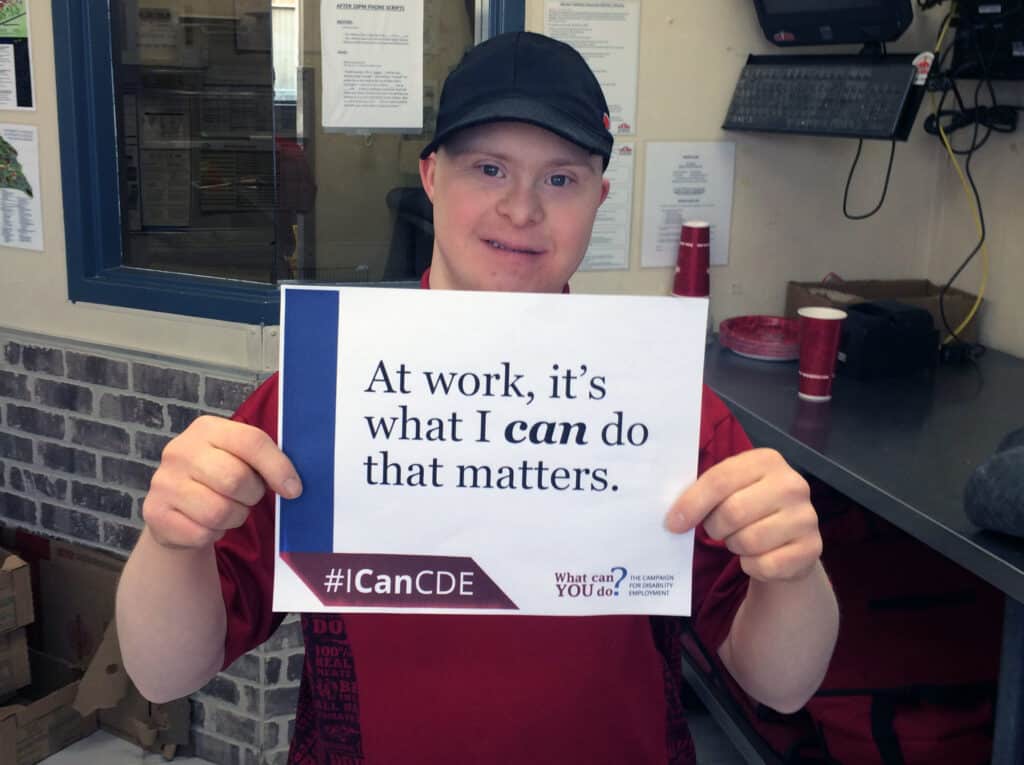 Empowered worker holds sign emphasizing capabilities and importance of inclusion at work.
