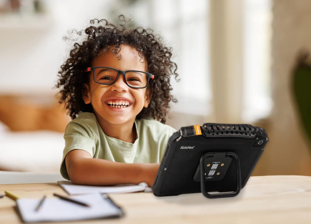 Joyful child using a Quicktalker Freestyle device for learning and discovery.