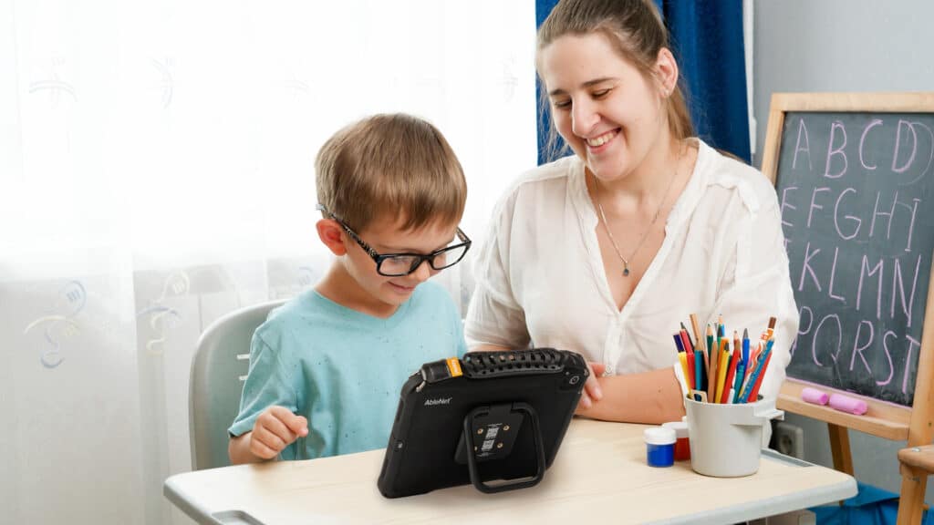 Child and caregiver enjoying learning together with a tablet and colorful supplies.