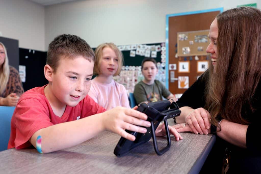 Student engaging with a Quicktalker Freestyle in a classroom, learning in a collaborative environment.