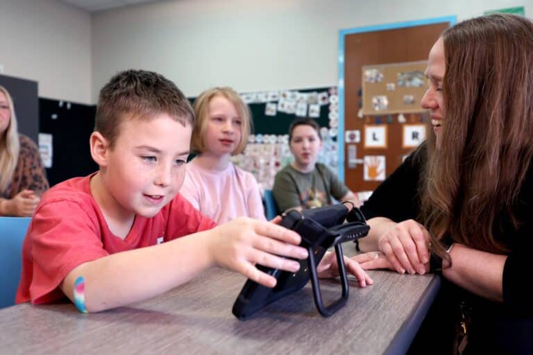 Student engaging with a Quicktalker Freestyle in a classroom, learning in a collaborative environment.