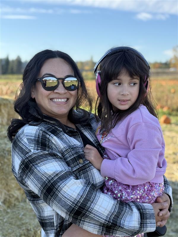 Happy mom and daughter enjoying an autumn day in a pumpkin patch.