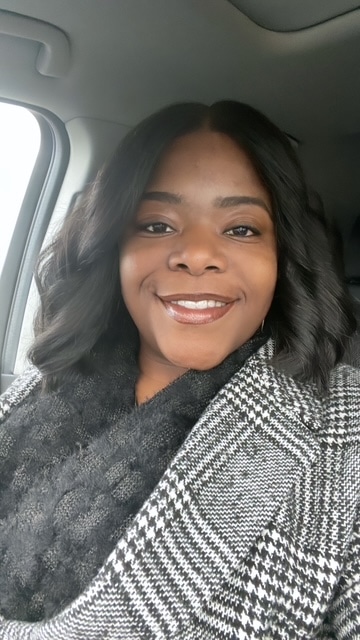 Smiling woman in a stylish coat taking a selfie in a car.