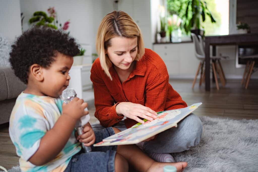 SLP and young boy enjoy reading a book and singing together at home.