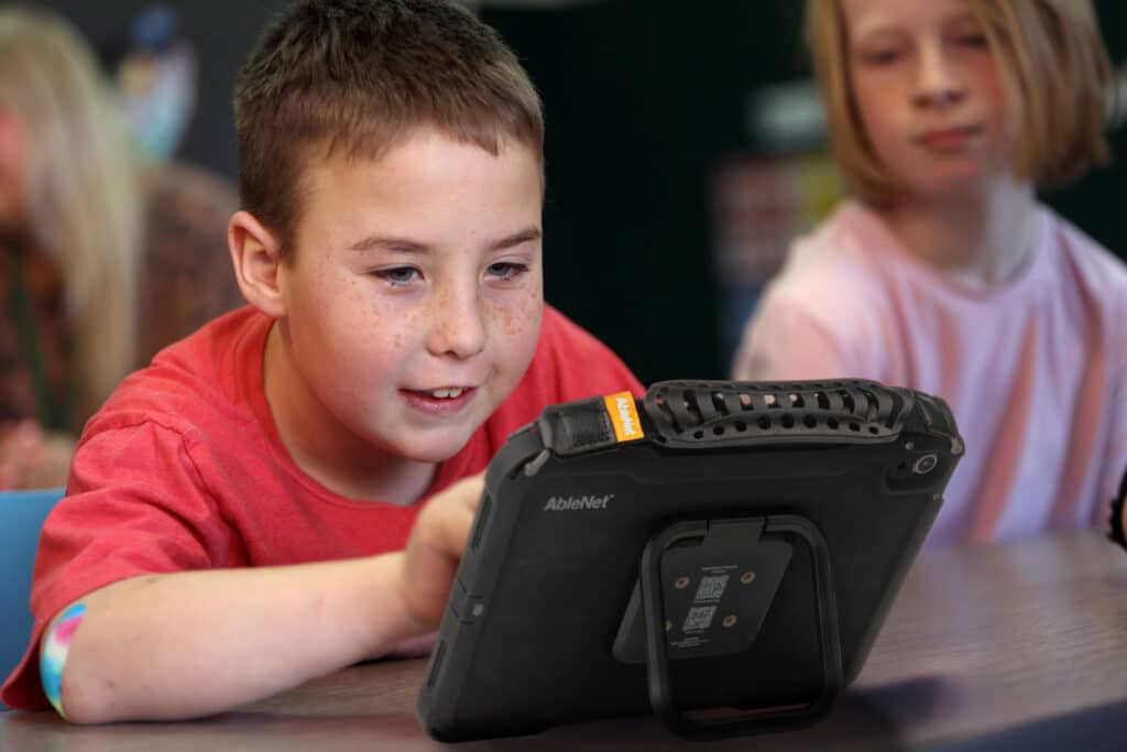 A child learning and engaging with a tablet in a classroom setting.