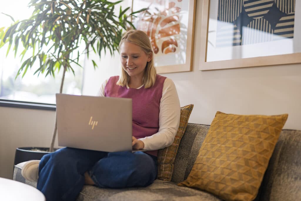 Woman working from home on a laptop in a cozy office setting.