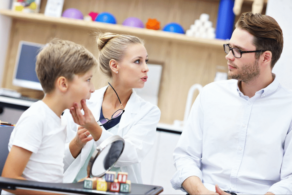 Child engaging in speech therapy with a clinician and parent.