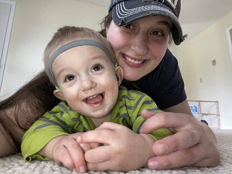 Happy mom and baby share joyful smiles while playing together on the floor.