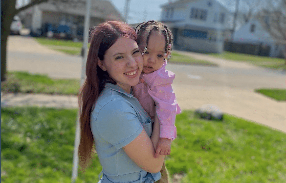 A joyful mother and child smiling together in a sunny outdoor setting.