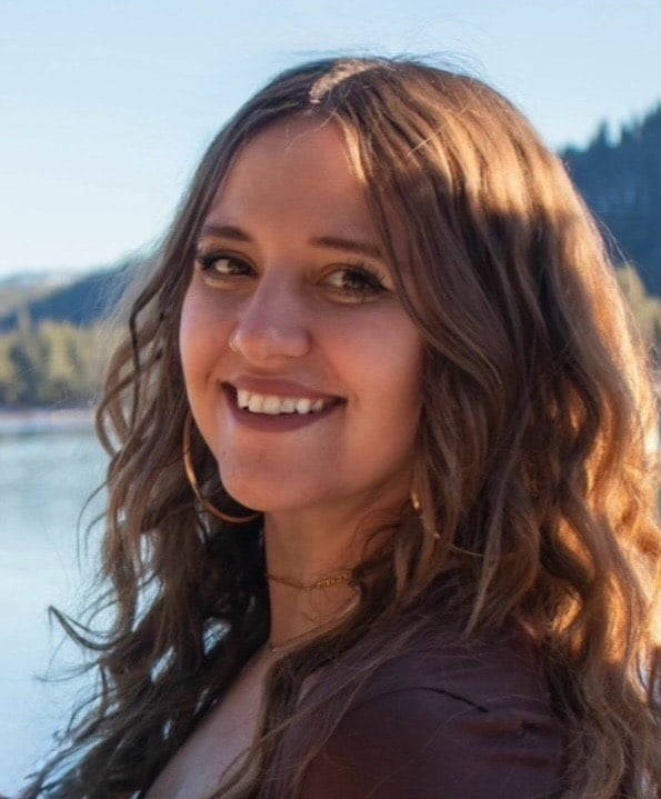Smiling woman by the lake showcasing beauty and nature in a serene setting.